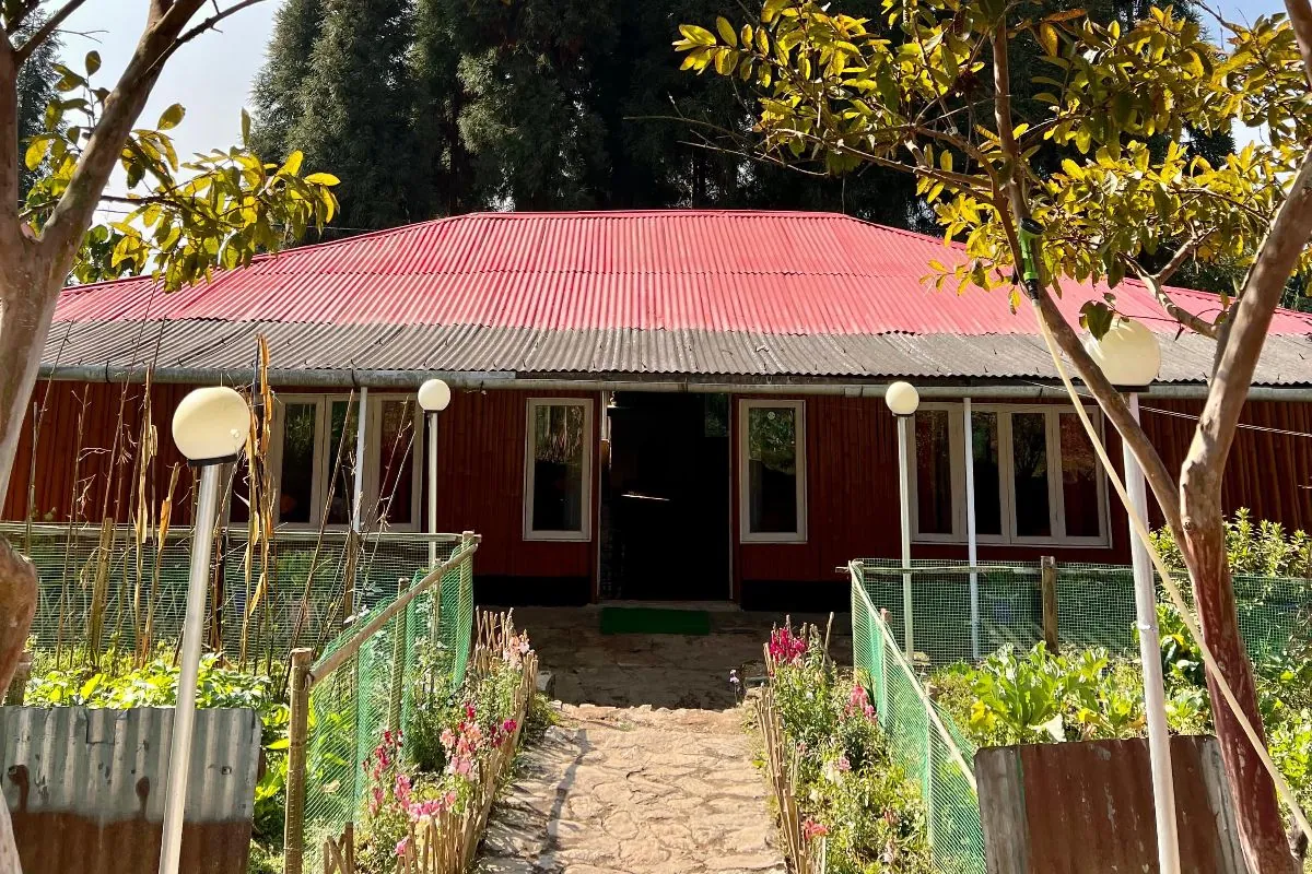 Homestays in Sikkim – a red-roofed hillside homestay with its kitchen garden below the tree line